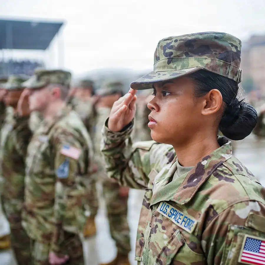Airmen and Guardians salute in formation at a retreat ceremony.